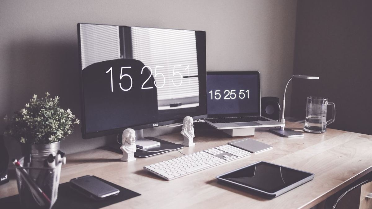 Office desk with desktop monitors, laptop and tablet
