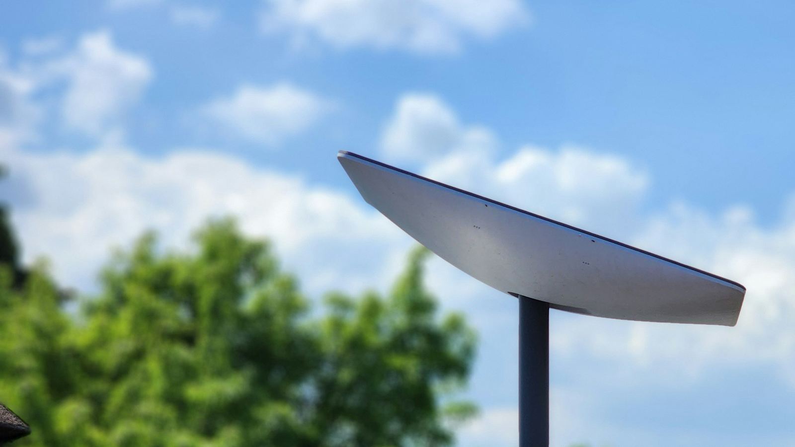 Starlink satellite internet dish on a rooftop mount under a blue sky